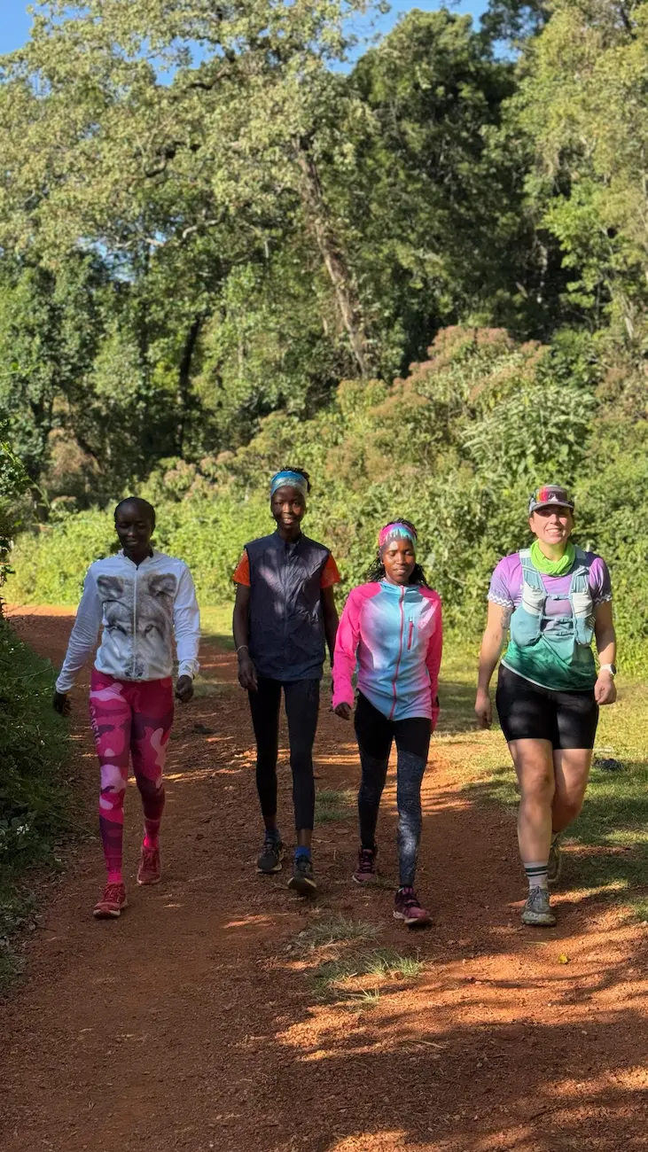 Corredoras de trail caminando por sendero de tierra roja en Kenia durante el training camp 2027